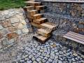 how to solve the steep entrance to the water on the dam. oak beams stacked and screwed together in a chaotic direction on top of each other. gabion slope go down the stairs