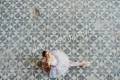 Ballerina sitting on a colorful rustic tiles and looking into the camera